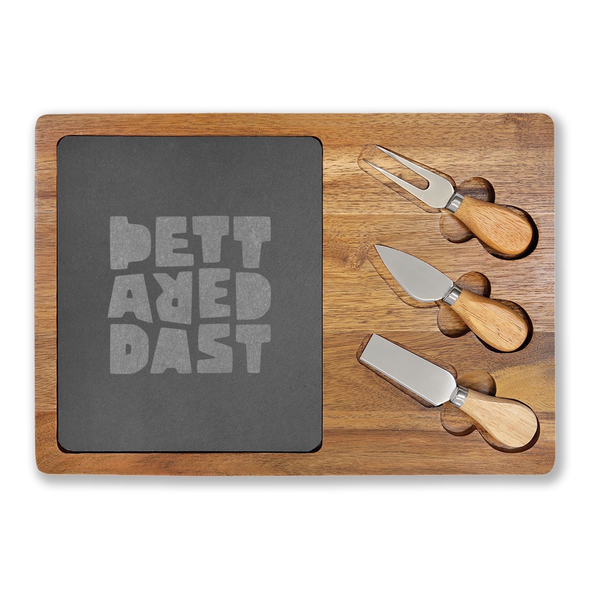 The Printify Charcuterie Board (Engraving) features a stylish acacia wood design with a dark slate center engraved "BETTERED PAST" and includes three wooden-handled cheese knives in side slots—perfect for any charcuterie spread.