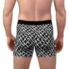 A person faces away from the camera, wearing Printify Men's Boxer Briefs (AOP) with a black and white pattern and a lightweight black waistband.